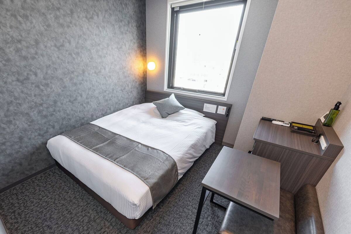 Habitación de hotel ordenada con cama, escritorio y ventana que ofrece vistas.