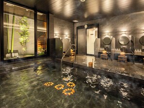 Un spa moderne doté d’une grande piscine chauffée, de tabourets en bois et d’une plante en bambou.