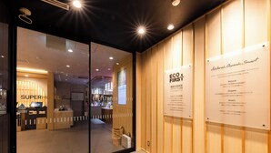 Un interior de hotel con una recepción, un muro de cristal y paneles de madera.