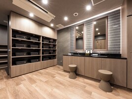 Un bagno moderno con mobili in legno, un grande specchio e due sgabelli.