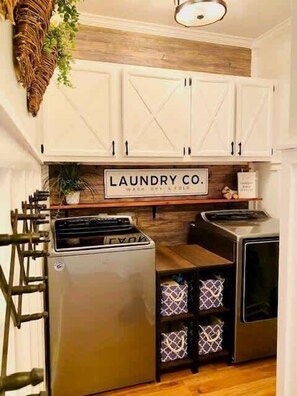A laundry room with a sign reading "LAUNDRY CO." and a washing machine. - Sleep Eat Beach Repeat, Spacious Poolside Retreat (Conway)