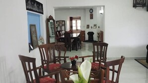 A dining area with a checkered tablecloth, wooden chairs, and a vase with a white flower. - Silver Meir Bungalow (Nuwara Eliya)