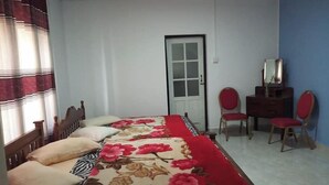 A bedroom with a bed, two chairs, a dresser, and a door. - Silver Meir Bungalow (Nuwara Eliya)