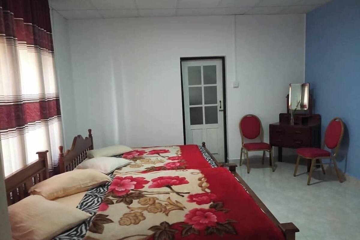 Ein Schlafzimmer mit einem Bett, zwei Stühlen, einem Schminktisch und einer Tür.
