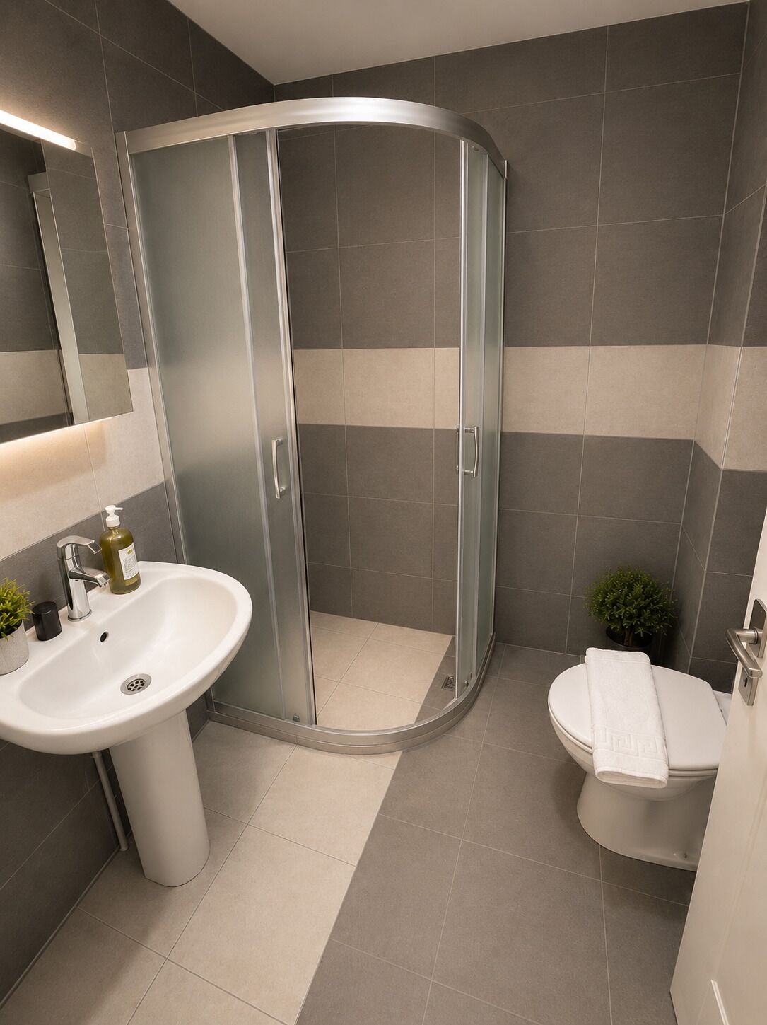 A modern bathroom with a curved shower enclosure, a white sink, and a toilet.