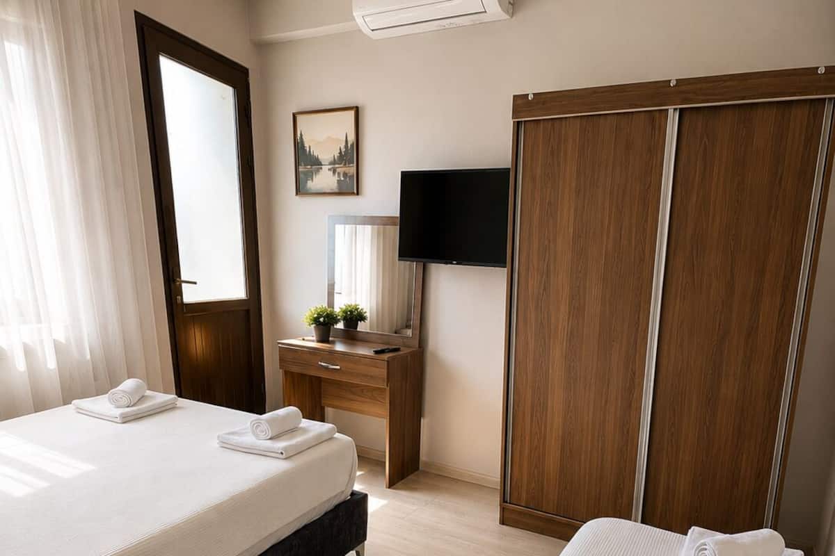 A hotel room with two beds, a desk, a TV, and a wardrobe.