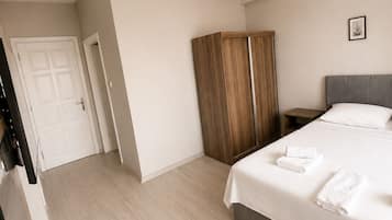 Un dormitorio con cama, armario, mesita de noche y lámpara colgante.