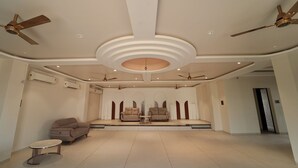 Uma sala de estar ampla com palco, sofás, ventiladores de teto e iluminação embutida.