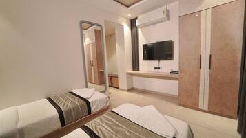 Une chambre d’hôtel avec deux lits simples, une armoire, une télévision et un miroir.