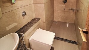 Casa de banho moderna com pia, espelho, chuveiro e prateleira de arrumação.