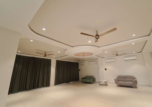 A spacious living room with a high ceiling, recessed lighting, and ceiling fans. - Pandharipuram Palace (Pandharpur)