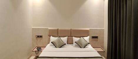 Una habitación de hotel moderna con una cama grande, un ventilador de techo y una cortina oscura en la ventana.