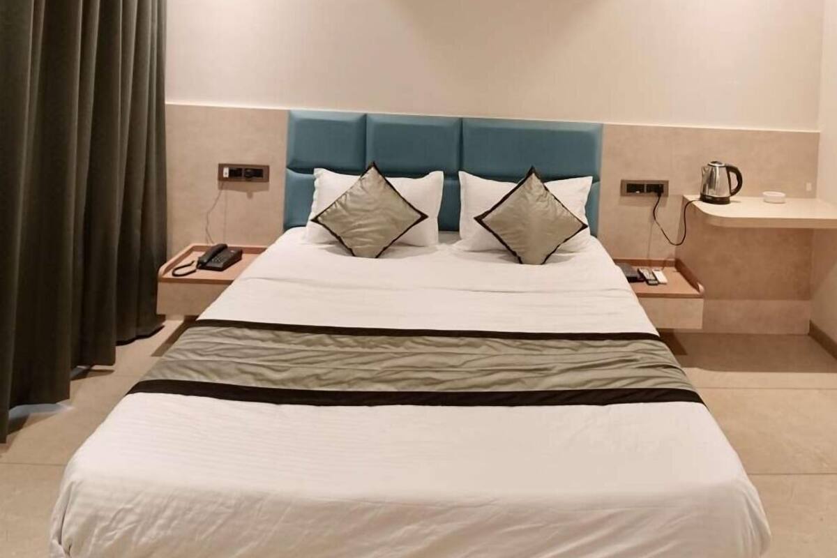 A modern hotel room with a large bed, a ceiling fan, a bedside table with a lamp, and a nightstand with a phone.