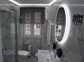 Ein modernes Badezimmer mit einer gläsernen Dusche, einer Toilette und einem Waschbecken mit Spiegel.