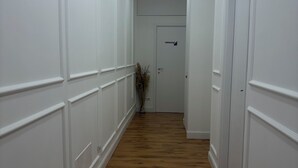 A hallway with white wainscoting and wooden flooring, leading to a door with a sign. - Sava House Entire apartment newly renovated. Cozy and quiet! (Roma)