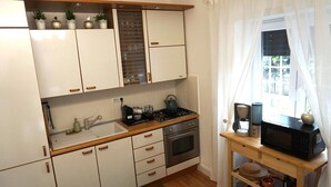 A compact kitchen with white cabinets, a wooden countertop, a gas stove, an oven, and a coffee maker. - Sava House Entire apartment newly renovated. Cozy and quiet! (Roma)