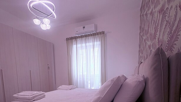 A bedroom with a bed, bedside tables, a ceiling light fixture, and a window with curtains. - Sava House Entire apartment newly renovated. Cozy and quiet! (Roma)