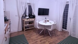A compact living space with a kitchenette, a dining area, and a TV mounted on the wall. - Sava House Entire apartment newly renovated. Cozy and quiet! (Roma)