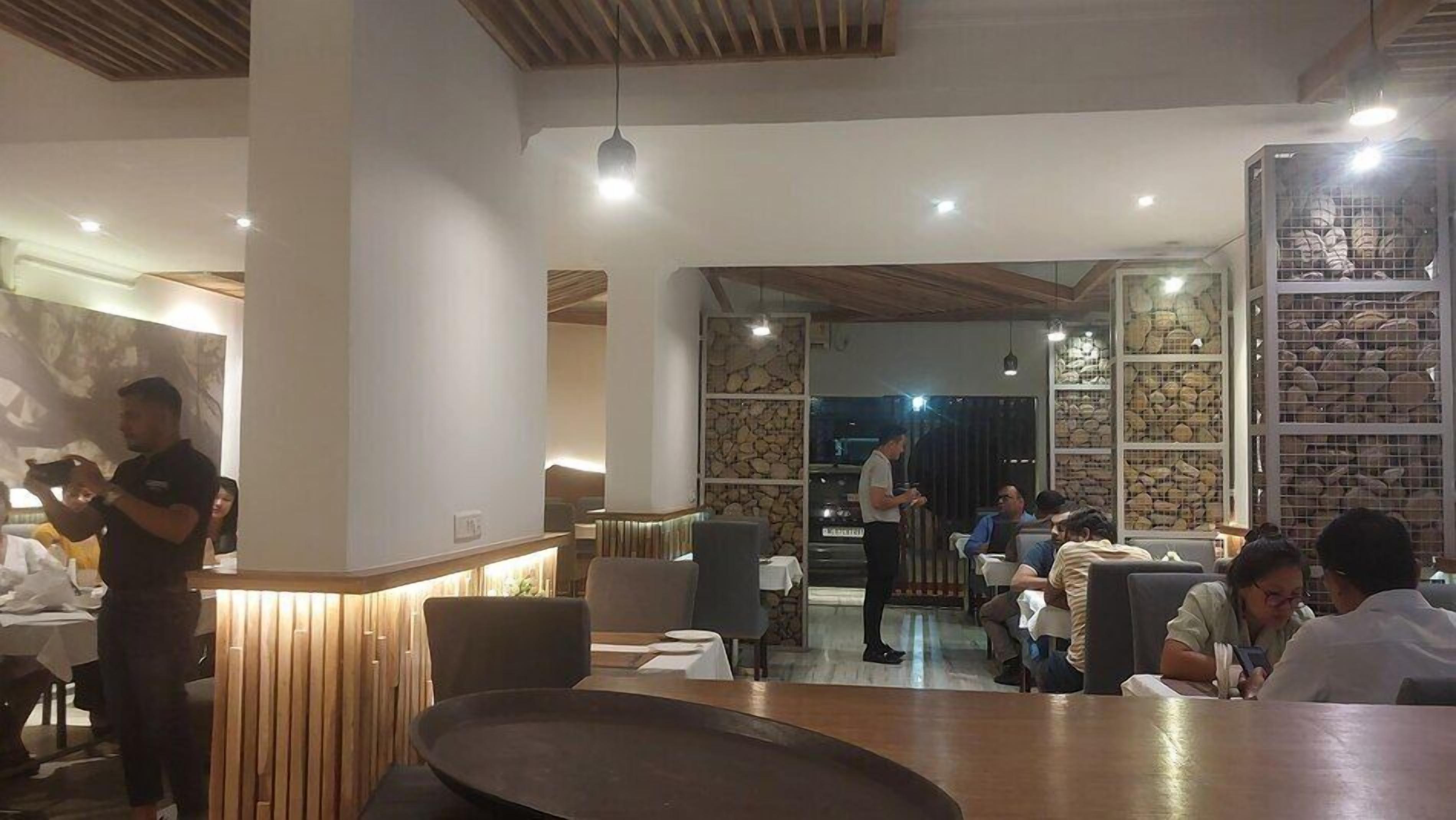 L’intérieur d’un restaurant, avec des éléments décoratifs en bois, un comptoir et des clients assis à des tables.