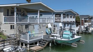 A waterfront property with a dock, a boat, and a building with a balcony. - Long Island Village Pet Friendly 857 (Port Isabel)