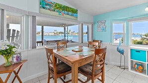 A dining area with a view of the sea, a painting of a beach house, and a starfish decoration. - 307 Long Island Village (Port Isabel)