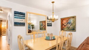 Une salle à manger avec une grande table, des chaises, un lustre et des œuvres d’art accrochées aux murs.
