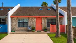 A two-story building with a red door, a small porch, and a blue fence.