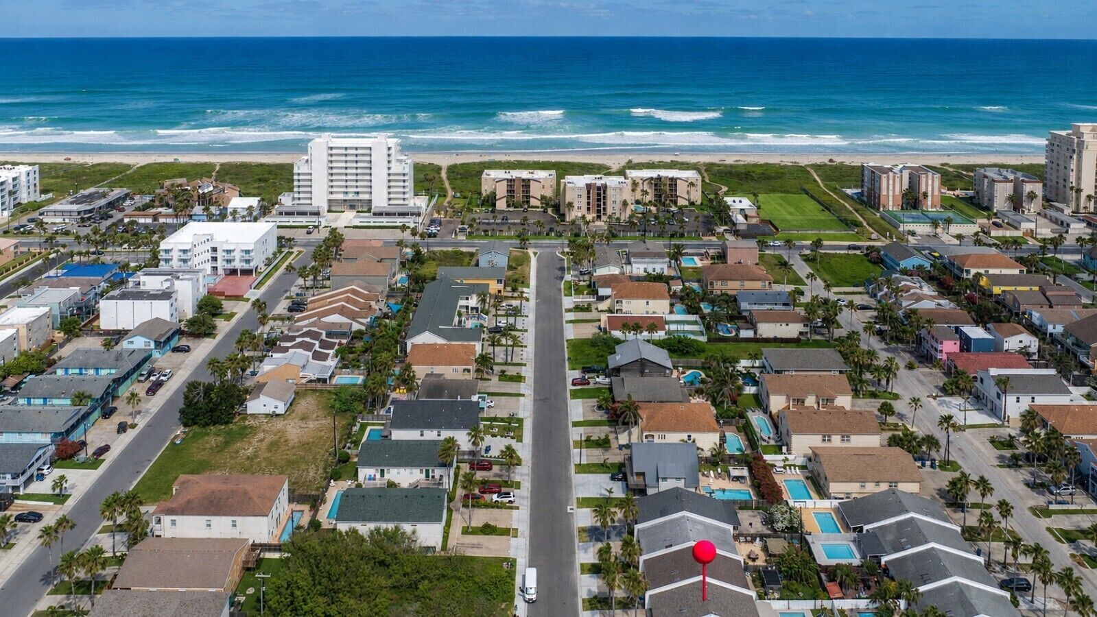 Vista aérea de una zona residencial costera con edificios, caminos y una playa.