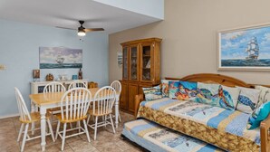 Una habitación acogedora con cama, una mesa de comedor con sillas, un armario y obras de arte en las paredes.