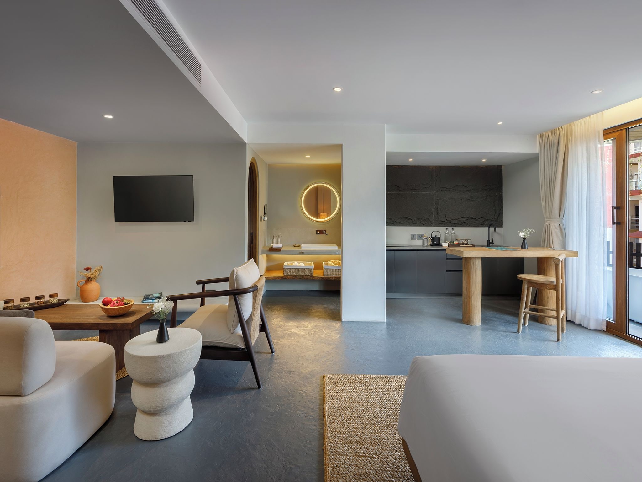 A modern hotel room with a living area, a dining space, and a kitchen.