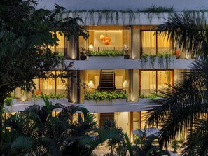 Un immeuble à plusieurs étages doté de balcons, d’un escalier et d’un éclairage intérieur.