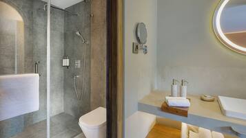 A modern bathroom with a glass-enclosed shower, a toilet, and a vanity with a mirror and toiletries.