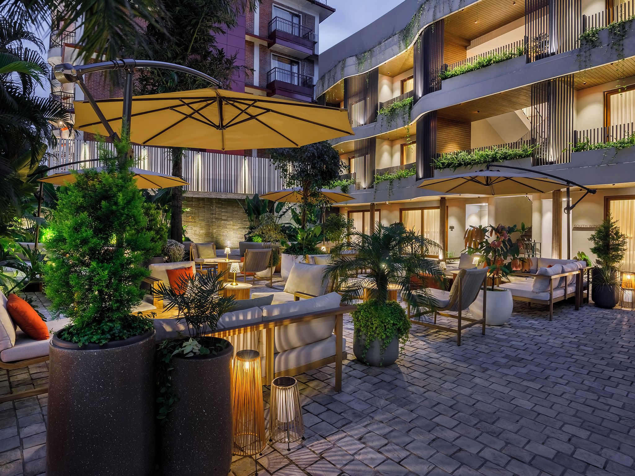 A hotel courtyard with outdoor seating, planters, and a building with balconies.