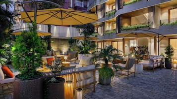 A hotel courtyard with outdoor seating, planters, and a building with balconies.