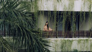 A person sitting on a balcony with hanging plants. - Bagaincha Resort & Spa (Pokhara)