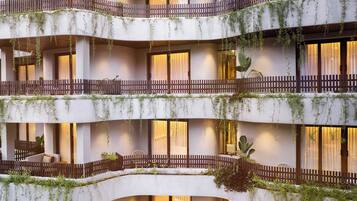Un hotel de varios pisos con balcones, zonas de estar interiores y plantas.