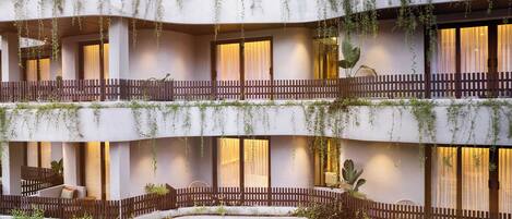 A multi-story hotel with balconies, indoor seating areas, and plants.