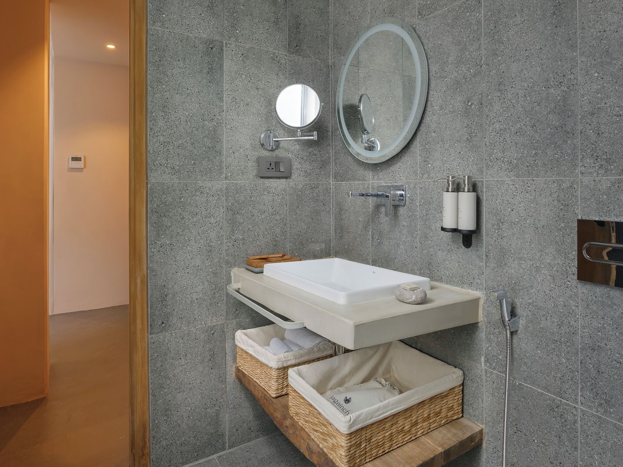 A modern bathroom with a white sink, a round mirror, and a built-in shower.