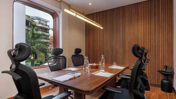 A conference room with a wooden table, four chairs, a large window, and a wooden wall panel.