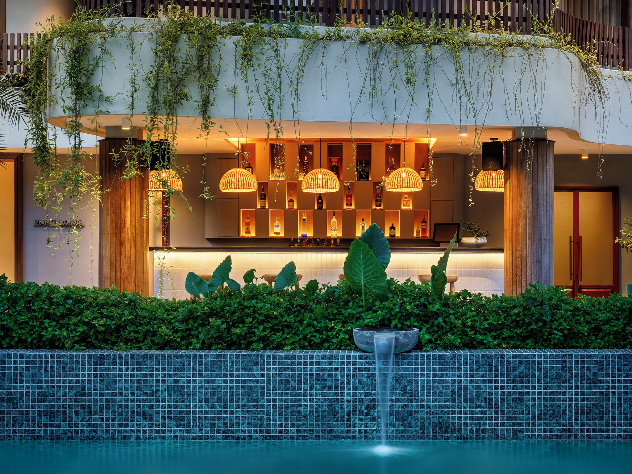 Zona de bar moderna con luces colgantes y vista a la piscina.