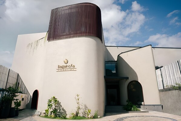 A modern building with a curved facade, a prominent entrance, and a logo on the side.