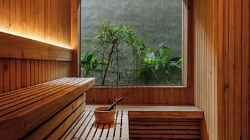 A wooden sauna with benches and a window overlooking greenery.