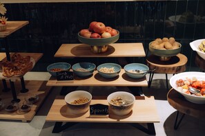 Un buffet proposant une variété d’aliments, notamment des fruits, des noix et du granola.