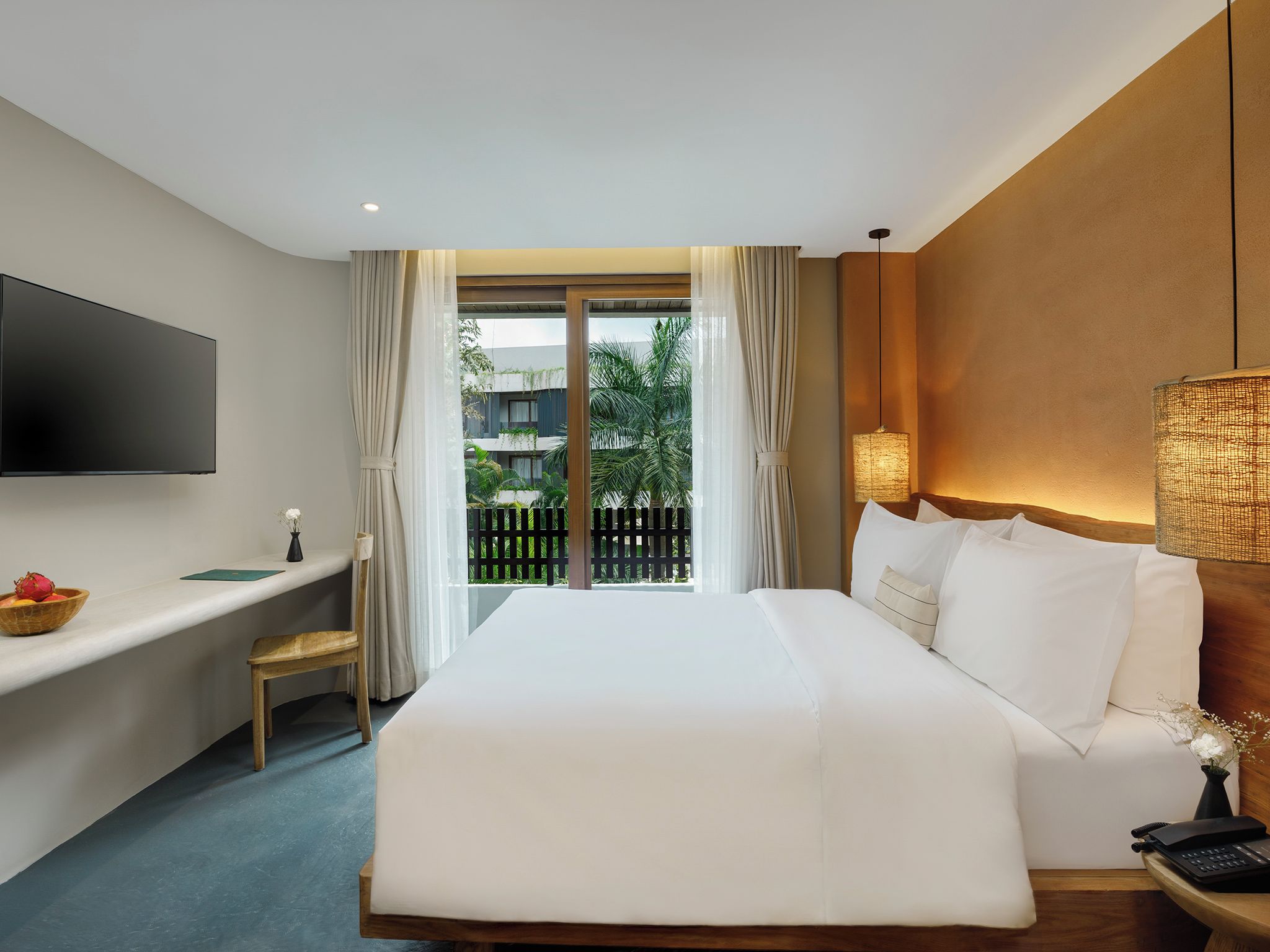 Une chambre d’hôtel équipée d’un lit, d’un bureau, d’une télévision, d’une lampe et offrant une vue sur l’extérieur.