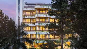 A multi-story hotel with balconies, a pool, and lush greenery.