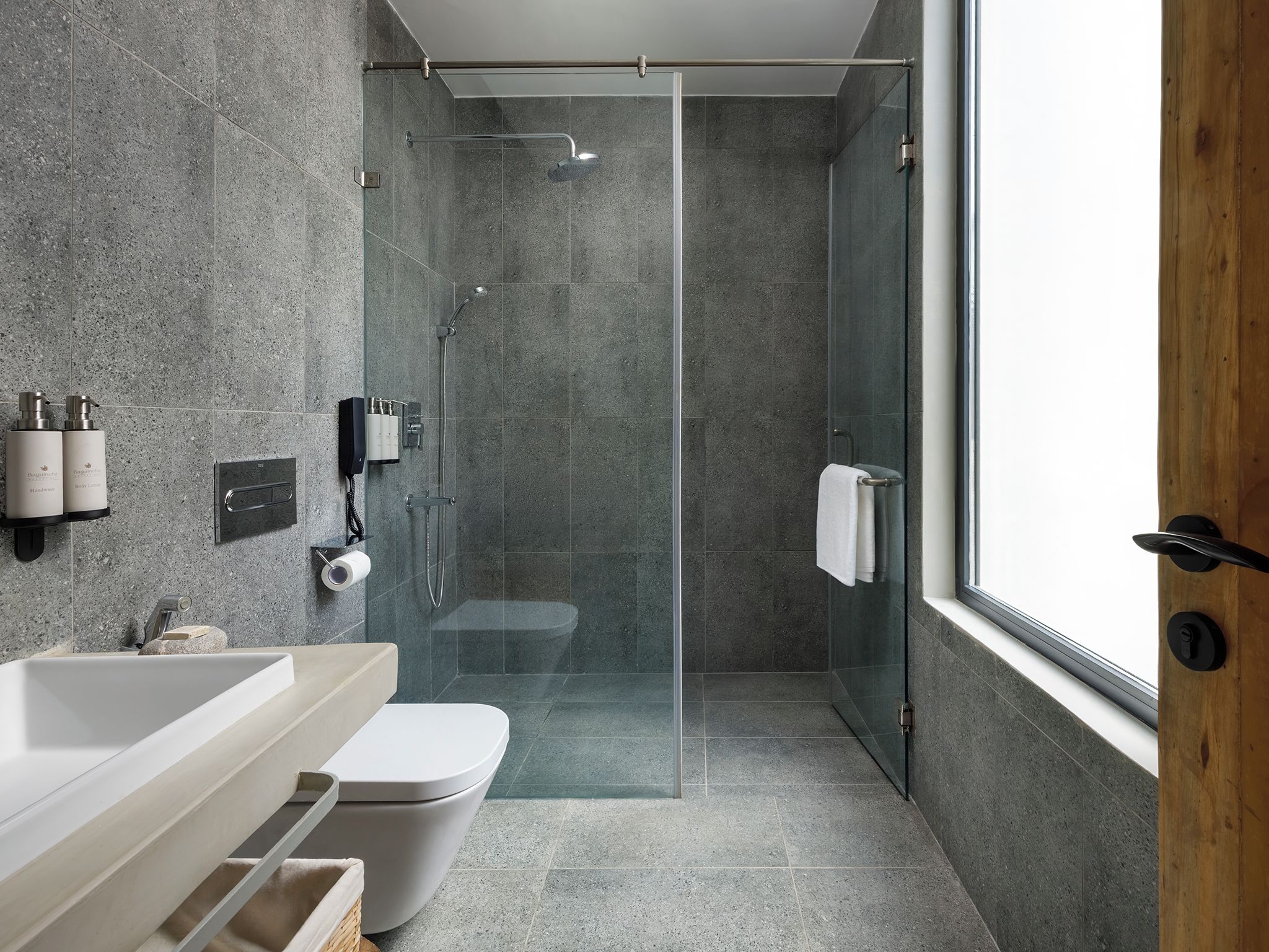 Un baño moderno con cabina de ducha acristalada, un lavabo blanco y un inodoro.