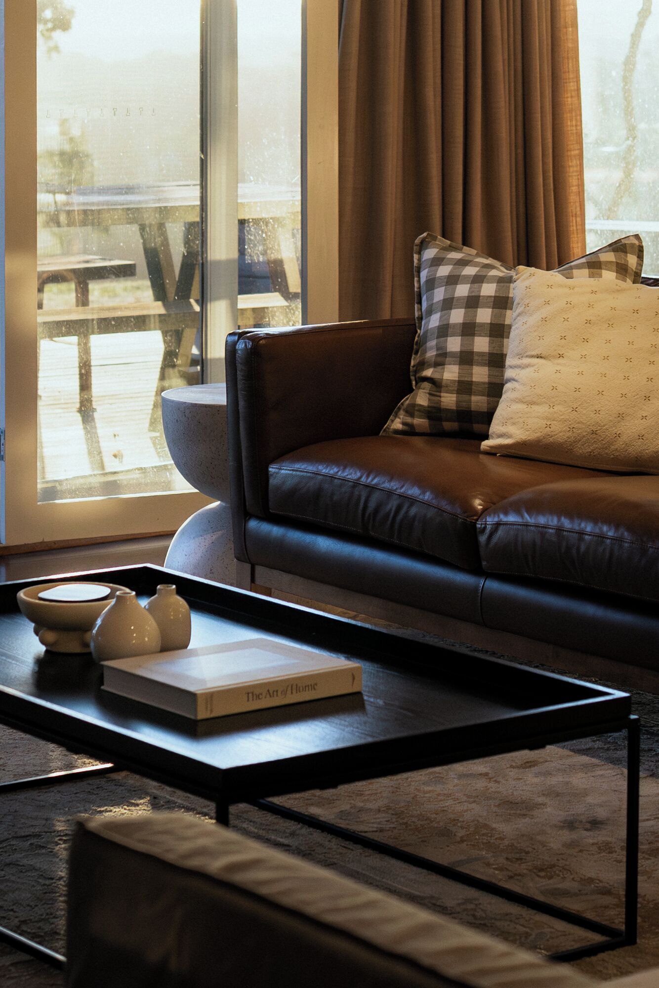 Un soggiorno moderno con un divano in pelle, un tavolino da caffè e un libro intitolato "The Art of Home".