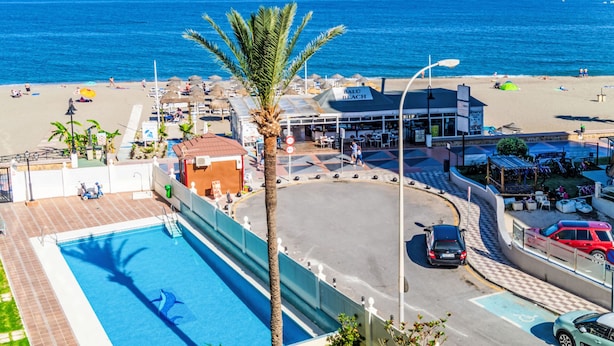 Vista frente a la playa con piscina, zona de playa con sombrillas y un cartel que indica Balú Beach.