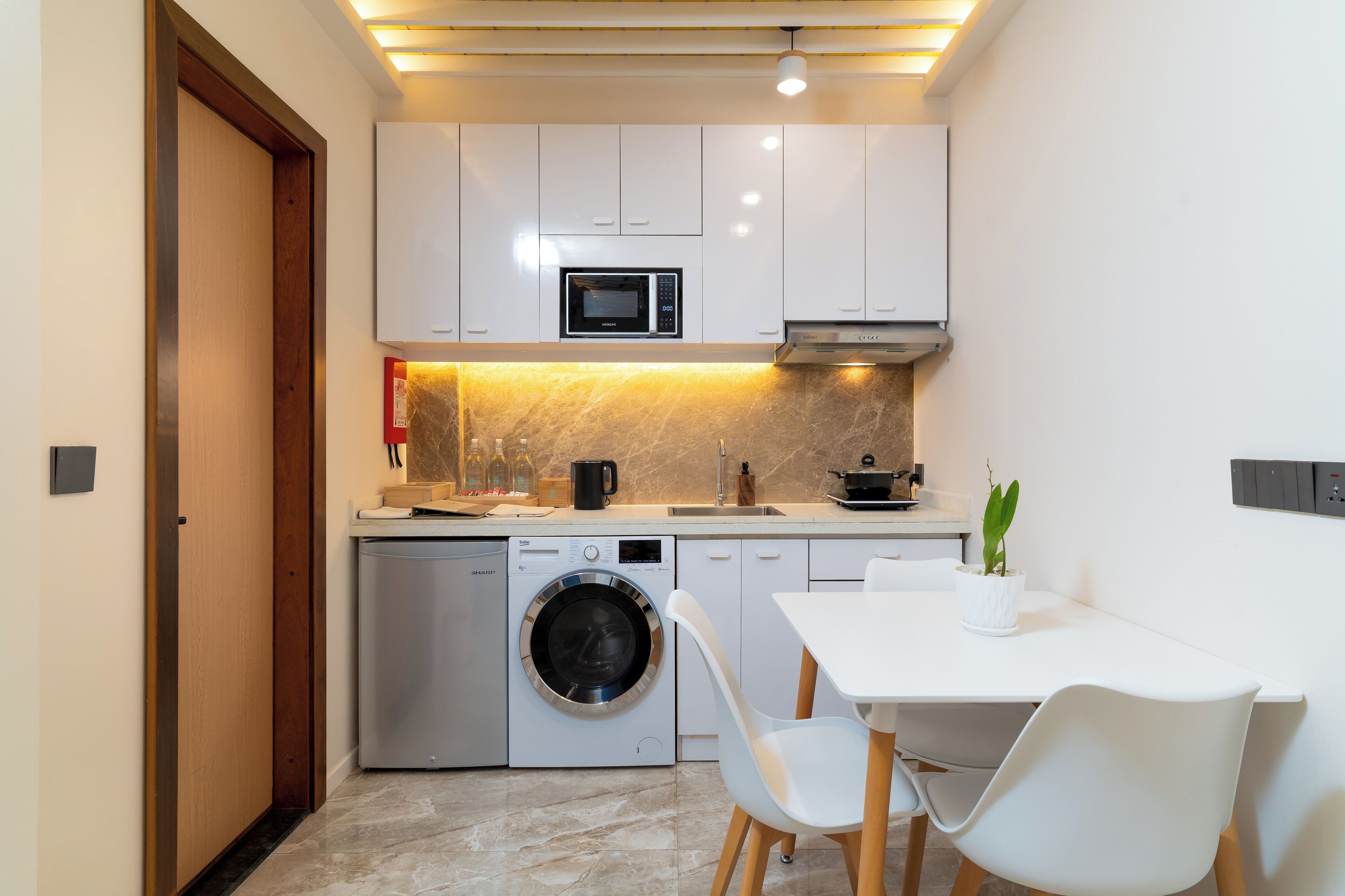 A compact kitchen with a built-in washing machine, a microwave, and a sink.