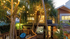 A modern building with a wooden deck, string lights, and tropical plants. - ARIA Beach Ukulhas (Ukulhas)